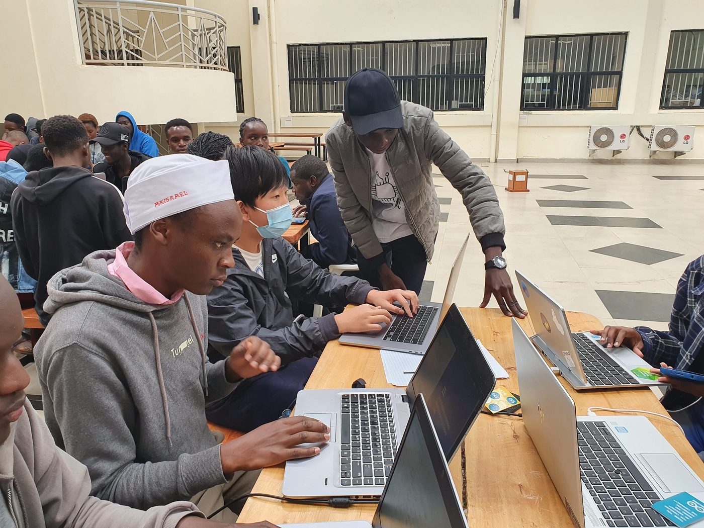 Arthur leaning in to help students at their laptops